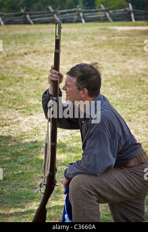 Confederate soldier reenactor kneels with his rifle on the Manassas National Battlefield. Stock Photo