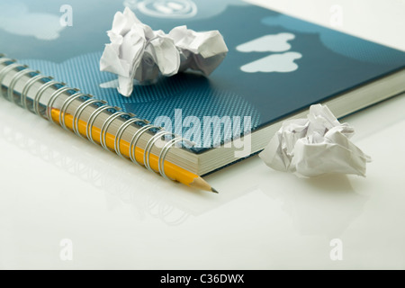 crumpled papers on notebook and yellow pencil Stock Photo
