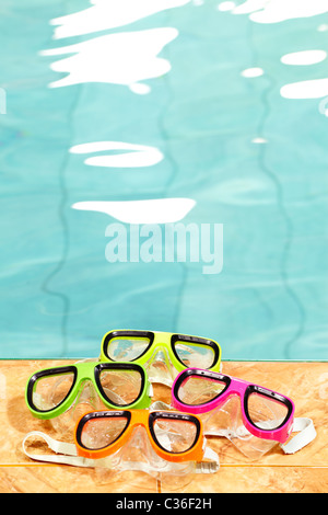 Four pairs of goggles lying in swimming pool Stock Photo