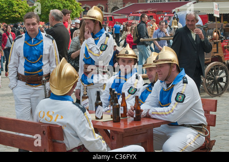 Volunteer village firefighters in historic uniforms drinking beer at street show on Firefighters Day at Rynek in Wrocław, Poland Stock Photo