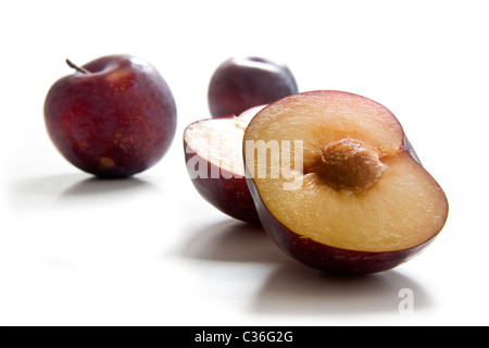 Two whole and half plums, variety Calita Stock Photo
