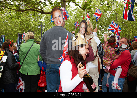 crowd celebrates the royal wedding with cartoon cut out faces of prince willim and catherine the duke and duchess of cambridge