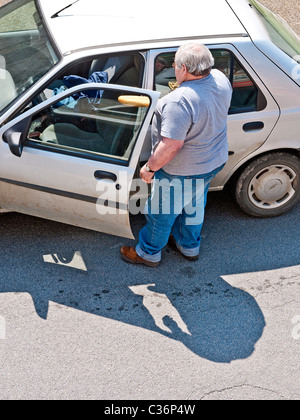 Overweight man opening car door - France. Stock Photo