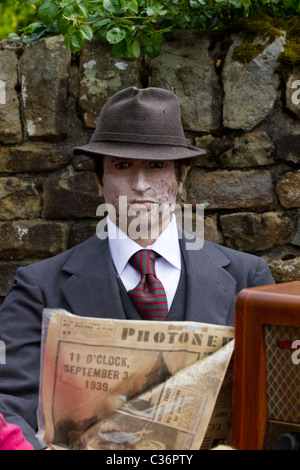 Wartime Seated Effigy figure wearing Trilby reading PhotoNews at the Wray Annual Scarecrow and Village Festival, Lancaster, Lancashire Stock Photo