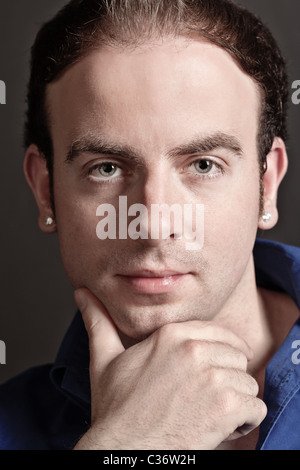 Portrait of a pensive young handsome man touching his chin Stock Photo