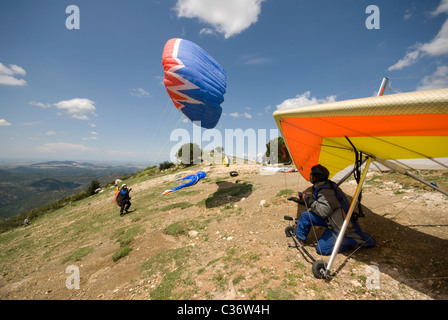Para glider pilot with his wing overhead about to launch and hang glider pilot  watching and waiting his turn to launch Stock Photo