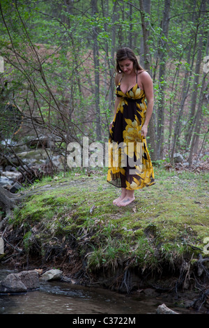 Lovely woman in yellow and black dress standing outside on a creek bank Stock Photo