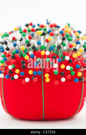 Red pin cushion with multi colored pins stuck in cushion Stock Photo