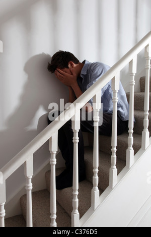 Young male sitting on the stairs alone and upset. Stock Photo
