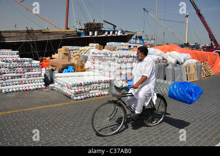 Local man riding bicycle on promenade, Dubai Creek, Deira, Dubai, United Arab Emirates Stock Photo