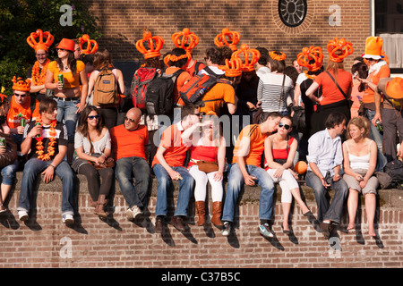 Queensday, the Queen's birthday in Amsterdam. Visitors, dressed up in orange, watching the Canal Parade in the Prinsengracht. Stock Photo