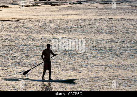 A stand up paddle boarder in silhouette, Sans Souci Beach, Honolulu, Hawaii. The beach is also known as Kaimana Beach. Stock Photo