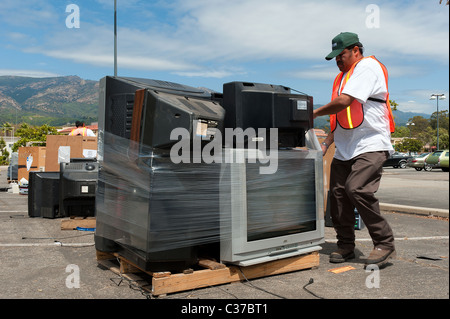 Recycling worker is wrapping with plastic  a palette of old televisions as electronic waste for recycling in a collection center Stock Photo