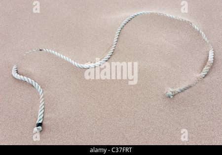 A piece of old rope lying on a sandy beach. Stock Photo