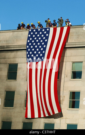 Military members rendered honors as fire and rescue workers unfurled a huge American flag over the side of the Pentagon during r Stock Photo