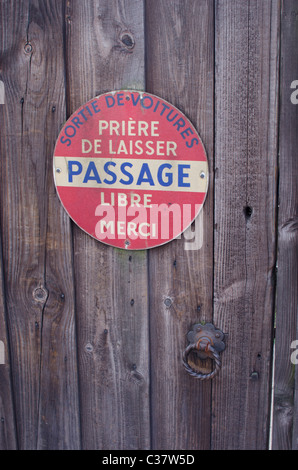 Polite no parking sign, in French, on wooden gate/door. Stock Photo
