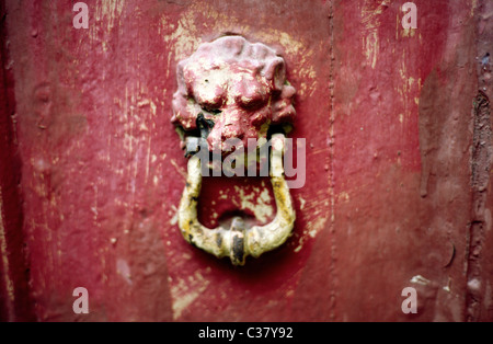 Painted over brass door knocker on a red wooden home entrance door in Victoria (Rabat) on the Maltese island of Gozo. Stock Photo
