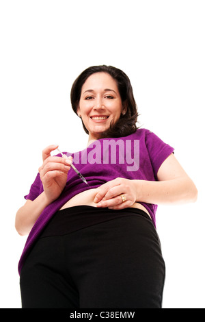 Attractive happy diabetic woman injecting insulin in her belly for health, isolated. Stock Photo