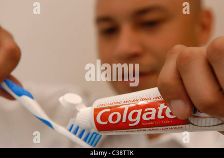 A tube of Colgate toothpaste being used in a bathroom. Stock Photo