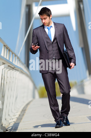 Man walking looking at phone Stock Photo