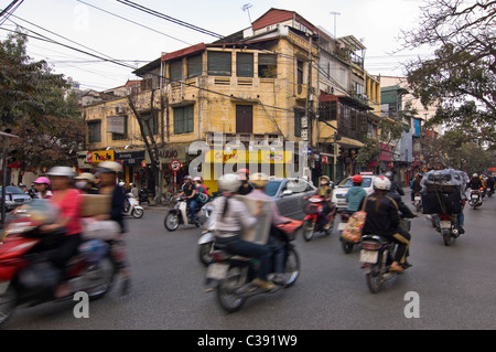 Horizontal wide angle of disorganised chaos on Hanoi's streets with people on mopeds, motorbikes & scooters at rush hour Stock Photo