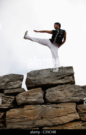 Chinese man doing martial arts on top of large rocks Stock Photo