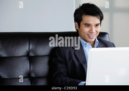 Chinese man using laptop and smiling Stock Photo