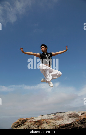 Chinese man jumping in air while doing a martial arts pose Stock Photo