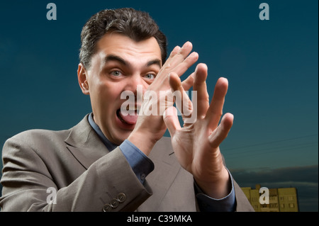 man in a suit against the evening sky shows tongue Stock Photo