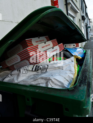 Discarded pizza boxes in an industrial green bin Stock Photo
