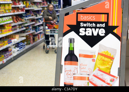 A Sainsbury's basics shelf display, with a shopper browsing in the background, North London. Stock Photo