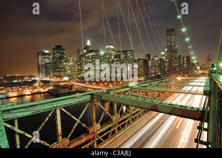 View of downtown Manhattan from the Brooklyn Bridge with traffic flying by. Stock Photo