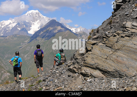Three mountain bikers look across a valley towards Mont Blanc in the French Alps. Stock Photo