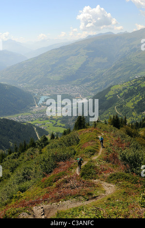 Two mountain bikers ride a ridge  trail down the mountain towards the town of Bourg-Saint-Maurice in the French Alps. Stock Photo