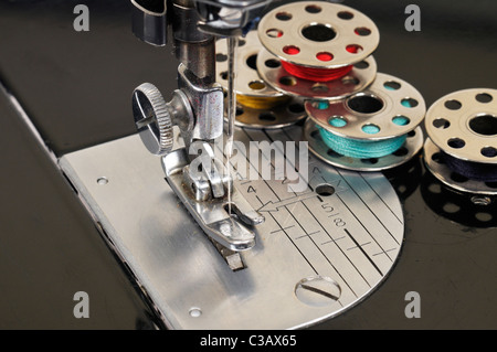 Threaded needle and bobbins spooled with thread of an antique Singer sewing machine close-up. Stock Photo