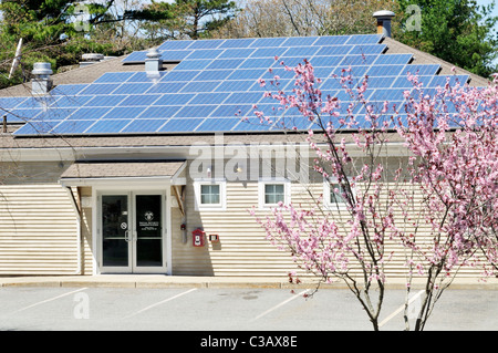 Solar panels installed on  roof of a commercial building on a sunny blue sky day Cape Cod, Massachusetts, USA Stock Photo