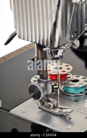 Threaded needle and bobbins spooled with thread of an antique Singer sewing machine close-up. Stock Photo