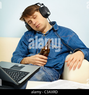 A young man fell asleep at home on the couch with a beer Stock Photo