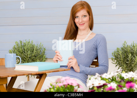 Summer terrace happy redhead woman relax with book in garden Stock Photo