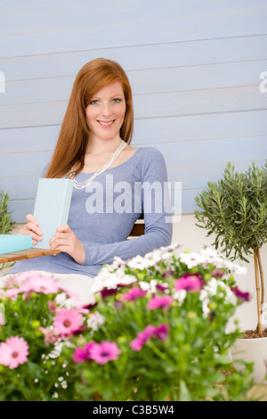 Summer terrace redhead woman relax with book in garden Stock Photo