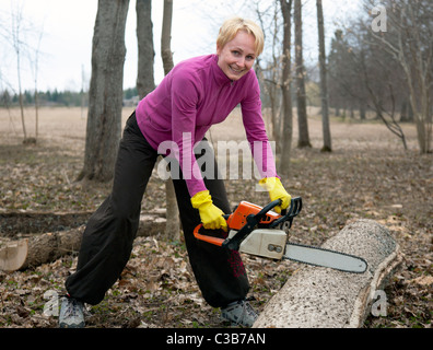 Happy Emotional Caucasian Woman Cutting Log with Chainsaw Stock Photo