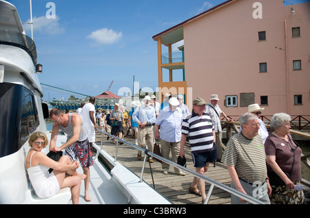 Tourists arriving from Cruise Ship alongside tourists on catamaran bound for Barbuda - in Antigua Stock Photo