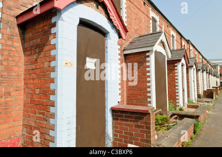Entire street of abandoned and boarded up houses in a run-down area of a city Stock Photo