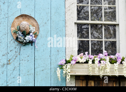 Picturesque Cape Cod barn with flowering window box and decorated straw hat on door. USA Stock Photo