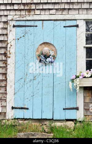 Picturesque Cape Cod barn with flowering window box and decorated straw hat on door. USA Stock Photo