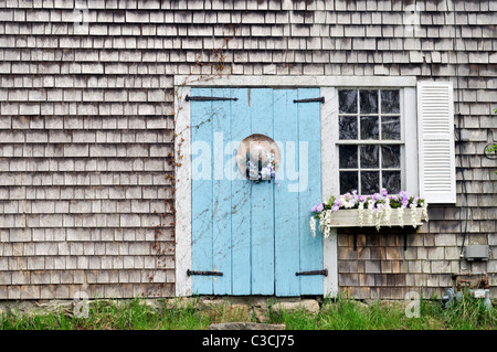 Picturesque Cape Cod barn with flowering window box and decorated straw hat on door. USA Stock Photo