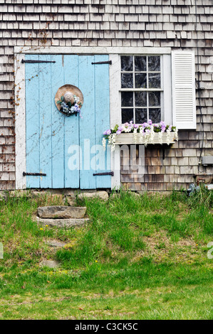 Picturesque Cape Cod barn with flowering window box and decorated straw hat on door. USA Stock Photo