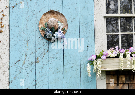 Closeup of picturesque Cape Cod barn door with flowering window box and decorated straw hat on door. USA Stock Photo