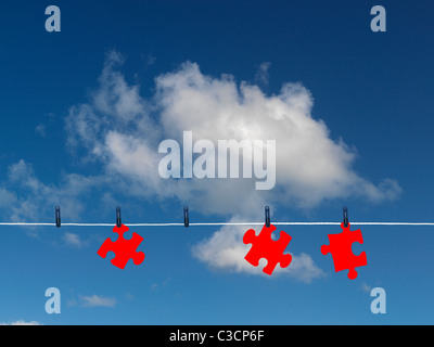 Jigsaw pieces on a clothes line isolated against a blue sky Stock Photo