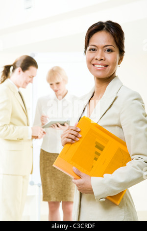Portrait of successful businesswoman looking at camera with her working co-workers at background Stock Photo